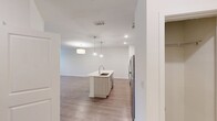 This contemporary 820 square foot apartment offers a thoughtfully designed living space on a single floor. The centerpiece is a spacious 240 square foot primary bedroom, complemented by a well-appointed closet for ample storage. The heart of the home is an open-concept kitchen and living room area, promoting a seamless flow for entertaining and daily living.

The kitchen showcases modern white cabinetry, stainless steel appliances, and a convenient island with a built-in sink, perfect for meal preparation and casual dining. Light-toned wood-look flooring extends throughout the main living areas, creating a cohesive and airy ambiance.

Large windows in the living room and bedroom flood the space with natural light, while offering picturesque views. Ceiling fans in multiple rooms ensure comfort and air circulation. The bathroom, though not directly visible, likely continues the modern aesthetic of the apartment.

The overall design emphasizes clean lines, neutral colors, and a bright, open feel. This apartment is ideal for those seeking a compact yet functional living space with contemporary finishes and a harmonious layout.