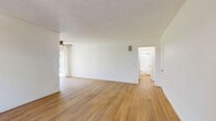 Located at 3526 Keystone Ave in Los Angeles, CA, this well-appointed one-bedroom, one-bathroom unit offers a thoughtfully designed single-floor layout with a clean, modern aesthetic throughout. Light hardwood flooring runs continuously across the living room, bedroom, and connecting spaces, lending warmth and visual continuity to the interior.

The living room is generously proportioned, featuring crisp white walls, a textured ceiling, and a wall-mounted heating unit. Natural light filters in through sheer curtains, creating a bright and airy atmosphere. A convenient coat hook rail adds a practical touch near the entryway.

The galley-style kitchen is a standout feature, showcasing warm wood cabinetry with mixed glass and solid panel doors, white quartz countertops, a matte black faucet with an undermount sink, and stainless steel appliances including a gas range and refrigerator. A sputnik-style chandelier adds a modern design accent overhead. In-unit washer and dryer are tucked neatly at the rear of the kitchen, accessible via a back door.

The bedroom is comfortably sized, featuring a mirrored sliding closet with a sleek black frame and windows dressed with sheer white curtains that invite natural light. The bathroom is clean and contemporary, with matte black fixtures, a shower-tub combo, open wall shelving, and a window for ventilation.