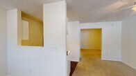 Located at 3810 Portofino Ct in Wilmington, NC, this single-floor residence offers a straightforward and functional layout designed for comfortable everyday living. The living area greets visitors at the front entry, featuring plush carpeted flooring, textured ceilings, and multiple windows dressed with blinds that allow generous natural light to fill the space. A ceiling fan provides added comfort, and a wall-mounted air conditioning unit ensures year-round climate control.

The kitchen is efficiently arranged with white cabinetry, an electric range, a sink, and a refrigerator, all set atop rich, dark hardwood-style flooring that extends into the adjacent hallway. An electrical panel is conveniently accessible nearby.

The bedroom areas are carpeted and neutral in tone, offering clean, move-in-ready spaces. One room features a ceiling fan with light fixture, while additional rooms provide quiet, versatile spaces suitable for sleeping or home office use. A dedicated closet offers practical storage.

The full bathroom is finished with dark hardwood-style flooring, a tub-shower combination, a vanity with sink, a towel bar, and a baseboard heater, maintaining a clean, white aesthetic throughout. Overall, the residence presents a practical and well-organized living environment in a convenient Wilmington location.