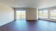 Located at 151 Andover Park E in Tukwila, WA, this single-floor unit presents a clean, contemporary design throughout. The open-concept living area is finished with rich hardwood-style plank flooring and features a sliding glass door leading to a private balcony, alongside additional windows that frame views of surrounding greenery and the neighborhood streetscape, filling the space with generous natural light.

The kitchen is a standout feature, showcasing granite countertops with a striking herringbone-patterned aqua tile backsplash, white shaker-style cabinetry with brushed hardware, and a full suite of stainless steel appliances including a range, microwave, dishwasher, and refrigerator. A granite-topped island with pendant lighting overhead adds both workspace and visual appeal.

The bedrooms are carpeted for comfort and well-lit by large windows with outdoor views. One bedroom includes a ceiling fan. Both bathrooms echo the kitchen's finishes, featuring granite vanity tops, white cabinetry, and wood-look flooring, with one bathroom offering a tub-shower combination. Neutral tones and consistent finishes throughout create a cohesive, modern ambiance.