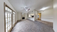 This single-floor residence offers a well-designed open-concept layout that connects the living, dining, and kitchen areas seamlessly. The spacious living room is a focal point of the home, featuring plush carpet flooring, a textured ceiling, a ceiling fan with light fixture, and a white-painted brick fireplace accented by a mirrored surround and a raised hearth. Built-in shelving flanks one wall, adding both function and character. French doors in the living area invite natural light and provide access to an outdoor space.

The kitchen is efficiently designed with granite countertops, cream-toned cabinetry, and black appliances including a refrigerator, range, and microwave. A peninsula with an undermount sink and pendant lighting above opens the kitchen to the living and dining areas, creating an inviting, connected atmosphere. Wood-look flooring runs throughout the kitchen.

The bedrooms are carpeted and well-proportioned, each with a ceiling fan and windows fitted with blinds for natural light and privacy. One bedroom includes direct access to a private bathroom and a walk-in closet with built-in shelving.

The bathroom features wood-look tile flooring, a granite-topped vanity with an undermount sink, and a full tub-shower combination with a chrome fixture and curtain rod.