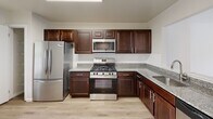Located at 32 Hawk Rd in Lawrence Township, NJ, this three-story, two-bedroom, three-bathroom home offers a well-organized layout spread across three distinct levels. The ground floor houses a spacious two-car attached garage with automatic openers, providing ample parking and storage space. The main living level features an open-concept kitchen and living room with warm hardwood-style flooring, large windows that invite abundant natural light, and a sliding glass door leading to an outdoor deck with greenery views. A dedicated living room on this floor also benefits from sliding door access and a bright, airy feel. The upper floor is home to the two bedrooms, including a generously sized primary suite complete with a walk-in closet, an adjoining bathroom featuring a glass-enclosed shower, granite countertops, and a natural light-filled window. The second bedroom is well-proportioned with its own closet and hardwood flooring. A conveniently located in-unit laundry room with full-size washer and dryer adds everyday practicality. Carpeted stairs with wood-railed banisters connect all three floors. Throughout the home, neutral tones, clean finishes, and thoughtful storage solutions create a comfortable and functional living environment.