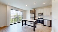Located at 3604 Rainbow Blvd in Kansas City, Kansas, this efficiently designed single-floor unit offers a thoughtful layout that maximizes every square foot. The open living and kitchen area is anchored by light-toned hardwood-style flooring and recessed lighting, creating a bright and welcoming atmosphere. A large sliding glass door leads to a private balcony, filling the space with natural light and offering pleasant outdoor views of the surrounding greenery and cityscape.

The kitchen is well-appointed with two-tone cabinetry — crisp white upper cabinets paired with rich dark lower cabinets — complemented by a classic white subway tile backsplash. Stainless steel appliances, including a refrigerator, range, microwave, and dishwasher, provide full functionality. Ample upper and lower cabinet storage ensures practical use of the space.

The bathroom showcases elegant marble-look tile flooring and matching wall tile in the walk-in shower, which features a glass enclosure. Dark wood cabinetry with modern hardware and a clean white countertop complete the refined aesthetic.

Throughout the unit, the design balances contemporary style with functional living, making it a well-equipped and visually cohesive space in the heart of Kansas City.
