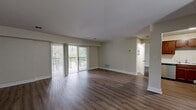 This 680-square-foot, one-bedroom, one-bathroom apartment at 150 Engamore Ln in Norwood, MA offers a practical and comfortable single-floor layout. The combined kitchen and living area forms the heart of the unit, featuring warm hardwood-style flooring throughout. The kitchen is equipped with rich wood cabinetry, marble-style countertops, stainless steel appliances including a dishwasher, microwave, and electric range, and a stainless steel sink. The open living area is bright and spacious, with sliding glass doors that lead to a private balcony enclosed by a black metal railing, offering serene views of mature trees and landscaped surroundings. The 190-square-foot primary bedroom is generously sized, with a window providing natural light and a sliding glass door that also opens to the balcony, extending the sense of space outdoors. A dedicated closet provides additional storage. The bathroom features a clean, white tub-shower combination with chrome fixtures, a grab bar, and wood-look vinyl flooring. Neutral wall tones and clean white trim throughout the unit create a cohesive, move-in-ready aesthetic.