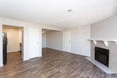 Located at 828 Calle Mejia in Santa Fe, New Mexico, this single-floor residence offers a well-organized layout with a variety of functional living spaces. The open living area is highlighted by rich, dark hardwood-style flooring, a textured ceiling, and a tiled fireplace that serves as a focal point of the room. Sliding glass doors with vertical blinds lead directly to a private balcony that overlooks surrounding greenery, bringing natural light and outdoor views into the space.

Adjacent to the living area, the entry zone features a ceiling fan and a dedicated dining area, maintaining the same durable hardwood-style flooring throughout. The galley-style kitchen is efficiently designed with white cabinetry, brushed nickel hardware, light stone countertops, a tile backsplash, and black appliances including a dishwasher and range, all set on wood-look flooring.

The bedrooms are carpeted for comfort and feature tall, narrow windows fitted with blinds that allow natural light while maintaining privacy. Each bedroom includes closet space.

The bathroom is clean and functional, featuring a full tub-and-shower combination with white tile surround, chrome fixtures, and wood-look flooring. Neutral gray tones are carried throughout the home, creating a calm and cohesive aesthetic well-suited to Santa Fe living.