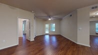 This single-floor residence offers a cohesive and functional layout highlighted by rich, dark hardwood flooring that flows seamlessly throughout the living areas, bedrooms, and bathrooms. The open living room is anchored by elegant crown molding, a ceiling fan with light fixture, and a glass-paned door that invites natural light and provides outdoor views. An arched doorway adds a classic architectural touch, connecting the living spaces with ease.

The kitchen is well-equipped with warm, dark-stained wood cabinetry, granite-style countertops, a tile backsplash, and stainless steel appliances including a range and over-the-range microwave. A breakfast bar provides additional prep and seating space, and track lighting illuminates the area effectively.

The bedrooms are generously sized, each featuring hardwood floors, ceiling fans, and windows with blinds that allow for ample natural light. The rooms offer a clean, neutral palette suited for a variety of furnishing styles.

The bathrooms are finished with dark wood vanities, grab bars for accessibility, and a tub-shower combination with tile surround. A frosted window in one bathroom allows for natural light while maintaining privacy.

Throughout the residence, neutral warm-toned walls, white trim, and consistent hardwood flooring create a unified and inviting atmosphere. Ample closet space and a practical entry area round out the thoughtful layout of this comfortable home.