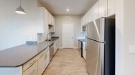 Located at 2051 Establishment Way in Charlotte, NC, this single-floor residence offers a thoughtfully designed layout with contemporary finishes throughout. The open-concept living and dining area features warm wood-look flooring, neutral toned walls, and a glass door that floods the space with natural light while providing outdoor access. A ceiling fan adds comfort to the main living space, which connects seamlessly to adjacent rooms.

The kitchen is well-equipped with light wood cabinetry featuring brushed nickel hardware, dark quartz countertops, a subway tile backsplash, and a full suite of stainless steel appliances including a refrigerator, range, microwave, and dishwasher. Ample cabinet storage lines the walls, offering generous functionality.

The bedrooms are carpeted for comfort, each benefiting from multiple windows dressed with blinds that invite natural light. The primary bedroom connects directly to a dual-vanity bathroom showcasing white quartz countertops, light wood cabinetry, a large wall mirror with contemporary lighting, and a tiled tub-shower combination with a classic white soaking tub. Wood-look flooring carries through the bathroom, completing the cohesive aesthetic.

Clean lines, neutral tones, and quality finishes define this move-in ready Charlotte residence.