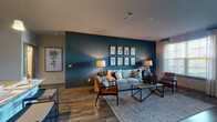 This single-floor residence in Spring Hill, Tennessee offers a thoughtfully designed layout with contemporary finishes throughout. The open-concept living area immediately draws attention with a dramatic deep teal accent wall adorned with a gallery of botanical artwork, warm wood-look flooring, and generous natural light streaming through large windows framed by sheer curtains. The kitchen is a standout, showcasing white shaker cabinetry, granite countertops, a full suite of stainless steel appliances, a subway tile backsplash, and a peninsula with bar seating — ideal for both daily living and entertaining. The bedrooms are comfortably scaled, featuring plush carpeting, multiple windows, and ample natural light. The primary bathroom offers a walk-in shower with framed glass doors, granite vanity countertops, and wood-look tile flooring, while a secondary bathroom mirrors the refined aesthetic with a tub-shower combo and similarly elegant finishes. A walk-in closet provides generous storage near the primary bath. Throughout the residence, a cohesive color palette of cool blues, warm neutrals, and dark accents creates a polished, modern ambiance that is both welcoming and sophisticated.