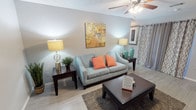 This single-story 2-bedroom, 2-bathroom residence offers a thoughtfully arranged floor plan that balances functionality and comfort. The living room is a welcoming space featuring light wood-style flooring, soft neutral-toned walls, a textured ceiling, and a ceiling fan with integrated lighting. The room provides a relaxed ambiance well-suited for everyday living.

The galley-style kitchen is a standout feature, outfitted with bold dark cabinetry that contrasts sharply against light countertops and a mosaic tile backsplash. Black appliances — including a refrigerator, electric range, and microwave hood — complete the modern aesthetic. A double-basin stainless steel sink and a tall built-in pantry cabinet add to the kitchen's practicality and storage capacity.

Both bedrooms are comfortably sized, each featuring ceiling fans with light fixtures, soft gray walls, light wood-style flooring, and closet storage. Natural light enters through windows dressed with curtains, creating a calm, restful atmosphere.

The two bathrooms maintain a clean, bright design with dark vanity cabinetry, light countertops, large mirrors with vanity lighting above, and white-tiled shower surrounds. The overall palette throughout the home is cohesive, combining neutral grays and crisp whites for a fresh, contemporary feel.