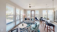 This single-floor residence offers a thoughtfully designed layout with multiple bedrooms, bathrooms, a bright living area, and a well-equipped kitchen. The living room is a standout space, featuring large windows with horizontal blinds that allow generous natural light to fill the room. Wood-look flooring, a ceiling fan, and an open connection to the dining area create a cohesive, contemporary feel.

The kitchen is outfitted with dark cabinetry, white countertops, stainless steel appliances including a refrigerator, electric range, and built-in microwave, complemented by a subway tile backsplash and pendant lighting above the sink.

Each bedroom features plush carpeting, ceiling fans, and ample natural light. One bedroom includes direct access to a bathroom with a navy blue double-vanity and white countertop, while another connects to a bathroom with a glass-enclosed shower and an adjacent walk-in closet with built-in shelving.

The bathrooms feature wood-look flooring, modern vanities, and clean finishes. A dedicated laundry area houses a full-size washer and dryer with overhead shelving, adding practical convenience to the unit's overall functional design.
