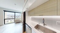 Located at 747 Hampden Ave in Saint Paul, Minnesota, this efficiently designed studio offers a thoughtfully arranged single-floor layout that maximizes every square foot. The open living area is anchored by large, floor-to-ceiling windows that flood the space with natural light and provide views of the surrounding neighborhood, complemented by warm light wood-tone flooring throughout.

The galley-style kitchen is outfitted with sleek, modern cabinetry in a combination of crisp white and natural wood-grain finishes, under-cabinet lighting, stainless steel appliances including a refrigerator, dishwasher, and oven, as well as a stainless steel sink — offering a fully functional cooking space within a compact footprint.

The bathroom continues the clean, contemporary aesthetic with a white vanity featuring undermount sink and brushed nickel hardware, wood-look flooring, a soaking tub with shower, and crisp white walls that create a bright, airy feel. A dedicated closet provides convenient storage. The unit's clean white walls, recessed lighting, and consistent modern finishes throughout give the space a cohesive, polished appearance well-suited for efficient urban living.