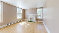 Located at 608 S Stevens St in Spokane, WA, this 2-bedroom, 1-bathroom unit offers a thoughtfully laid-out single-floor plan with classic character throughout. Original hardwood floors flow seamlessly across the living areas and bedrooms, lending warmth and timeless appeal to the space. The main living room is a standout feature, anchored by a decorative fireplace with a white painted mantle and framed by multiple large windows that invite abundant natural light and views of the surrounding neighborhood. Baseboard heating runs along the walls throughout, ensuring year-round comfort. A second living area connects to the kitchen, which is equipped with a coil-burner range, a full-size refrigerator, and open built-in shelving. The spacious primary bedroom includes a dedicated closet with a clothing rod and is illuminated by a ceiling fan light fixture, while the second bedroom features its own window with neighborhood views. Hallways connect the rooms efficiently across the well-organized floor plan. The bathroom is finished with hexagonal marble-style tile flooring, a combination tub and shower with white subway tile surround, and a wood-toned vanity. A dedicated laundry area adds everyday convenience, rounding out this well-appointed Spokane residence.
