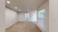This one-bedroom, one-bathroom unit at 817 S Euless Main St offers a practical and efficiently organized single-floor layout. The living area features neutral-toned carpet, recessed lighting, and a large window fitted with blinds that allows natural light to fill the space. A closet door and a hallway leading further into the unit are accessible from this main area.

The kitchen is thoughtfully designed with light wood-style flooring, white countertops, gray cabinetry, a gray tile backsplash, and black appliances including an electric range and dishwasher. A window above the counter provides a pleasant outdoor view and additional natural light. A separate dining area connects to the kitchen, featuring a sliding glass door that opens to a balcony overlooking the streetscape.

The bedroom is carpeted and finished in neutral tones, offering a comfortable and adequately sized private retreat. The bathroom includes a full tub-shower combination with white subway tile surround and brushed nickel fixtures. A hallway connects the rooms, contributing to the unit's organized flow. The overall aesthetic is clean, bright, and move-in ready.