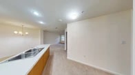 This single-floor residence offers a thoughtfully designed open-concept layout that seamlessly connects the kitchen and living areas. The kitchen is well-equipped with warm oak cabinetry, white appliances including a coil-top range, built-in microwave, refrigerator, and dishwasher, along with a double-basin stainless steel sink set into a light-colored countertop. A peninsula counter extends into the living space, enhancing both functionality and flow. The living and dining area features neutral carpet flooring and is illuminated by a classic chandelier, creating an inviting atmosphere. Recessed lighting throughout provides consistent, practical illumination. The bedrooms are generously sized, each finished with plush neutral carpeting and windows that allow natural light to filter in, offering outdoor views. Closet access is conveniently located within each bedroom. The bathroom is cleanly appointed with tile flooring, a walk-in shower with glass sliding doors, a soaking tub, and a wood-framed vanity mirror above an oak cabinet sink. Clean white walls and neutral tones are carried consistently throughout the space, lending a bright, cohesive aesthetic that is move-in ready and adaptable to a variety of furnishing styles.