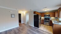 Located at 360 N St, Unit #32 in El Cajon, this single-floor residence offers a well-organized layout with functional living spaces throughout. The floor plan, as seen in the 3D overview, provides a clear separation between the living, sleeping, and kitchen areas, allowing for efficient use of space.

The kitchen is a notable feature, outfitted with warm-toned wood cabinetry extending to the ceiling for ample storage. Stainless steel appliances include a range with electric cooktop, an over-the-range microwave, and a full-size refrigerator. Granite-style countertops run along the U-shaped layout, complemented by a stainless steel sink positioned beneath a window that allows natural light in. The floor transitions from wood-look laminate in the living areas to tile in the kitchen.

The living and sleeping areas feature plush carpeting and neutral wall tones. The main living space opens to a sliding glass door leading to a private outdoor area with views of surrounding greenery. Additional bedrooms are served by windows fitted with blinds, providing natural light and privacy.

The bathroom includes a tub and shower combination enclosed with a glass sliding door, a toilet, and a vanity with a granite-style countertop and an integrated sink. Overall, the unit presents a clean, practical interior suited for comfortable everyday living.
