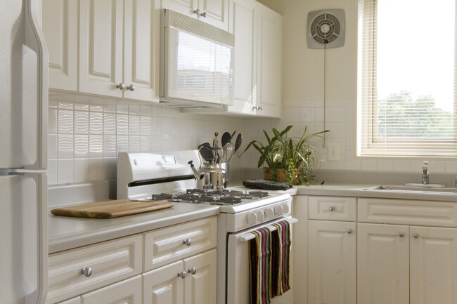 Kitchen with white cabinetry, white countertops, white appliances and tile backsplash - Avalon The Albemarle