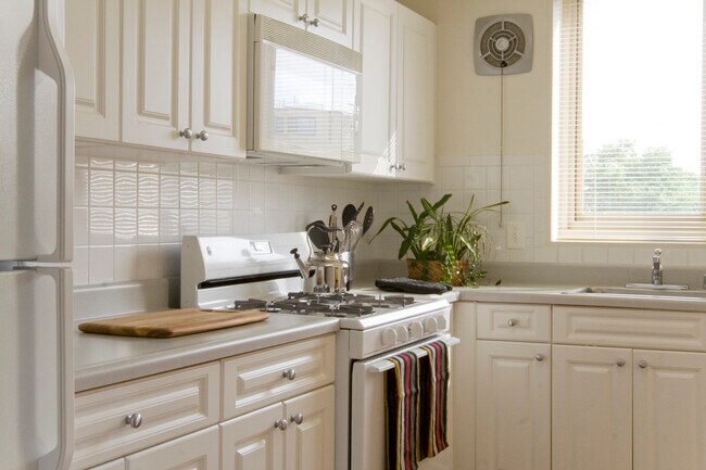 Cocina con armarios blancos, encimeras blancas, electrodomésticos blancos y salpicadero de azulejos - The Albemarle