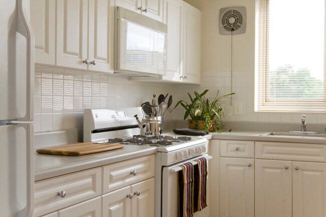 Kitchen with white cabinetry, white countertops, white appliances and tile backsplash - The Albemarle