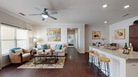 This single-floor residence offers a thoughtfully designed open-concept layout that seamlessly connects the living, dining, and kitchen areas. Rich, dark hardwood-style flooring flows throughout the main living spaces, complemented by crown molding and recessed lighting that add a polished touch. The living room is centered around a comfortable seating arrangement beneath a ceiling fan, with warm neutral walls providing an inviting backdrop.

The kitchen is a standout feature, boasting rich dark-walnut cabinetry, granite countertops, a classic subway tile backsplash, and a full suite of stainless steel appliances. A breakfast bar with wood-topped stools bridges the kitchen to the living area, making the space ideal for entertaining. A dedicated dining area sits just off the living room, completing the open social zone.

The primary bedroom offers plush carpeting, a ceiling fan, and a window that allows natural light to filter in through dark drape panels. A second bedroom provides similar comfort with carpeted flooring and a built-in closet. Both bathrooms are finished with granite-topped dark wood vanities, tile flooring, and well-lit mirrors, offering a consistent and refined aesthetic. The overall ambiance is warm, cohesive, and move-in ready.