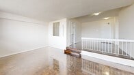 Located on the 11th floor at 125 Neptune Dr in Toronto, this one-bedroom, one-bathroom unit offers a well-organized layout across a single floor. The living area is a notable highlight, featuring a distinctive split-level design with a short staircase separating two zones, both finished with classic parquet hardwood flooring in a herringbone pattern. Large windows allow generous natural light to fill the space and frame views of the surrounding Toronto cityscape. The living area connects to a galley-style kitchen outfitted with white cabinetry, granite-speckled countertops, a double stainless steel sink with a white tile backsplash, and white appliances including a freestanding stove and refrigerator. Light ceramic tile flooring runs throughout the kitchen. The bedroom is a comfortable, well-proportioned room with its own large window offering city views and the same parquet flooring found in the living areas. The bathroom is clean and functional, featuring a white tiled shower-tub combination, a toilet, and a vanity with a granite-style countertop and mirror. Louvered closet doors throughout the unit add a classic design touch, and the white walls and bright, neutral palette give the space a clean, airy feel.