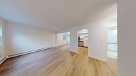 Located at 4 Brookside Dr E in Harriman, NY, this one-bedroom, one-bathroom residence offers a clean, bright, and efficiently designed single-floor layout. Light-toned hardwood-style flooring runs throughout the home, creating a cohesive and airy feel across every room.

The open living and dining area is generously sized, featuring large windows that invite natural light and views of the surrounding greenery. Baseboard heating runs along the walls, and a window AC unit provides climate control. The space flows naturally into the kitchen and dining area through an open archway.

The kitchen is well-appointed with white cabinetry, light countertops, and stainless steel appliances including a refrigerator, range, and dishwasher. The layout maximizes counter and storage space efficiently.

The bedroom is a comfortable, well-proportioned room with windows overlooking the outdoors and natural light throughout. It features dual closets with sliding doors, offering substantial storage. Additional closets are found throughout the home, totaling four, making storage a notable strength of this residence.

The bathroom is elongated and functional, with white tile flooring, a vanity with a blue countertop, a large mirror, and a full soaking tub with safety grab bars. The overall design is clean, neutral, and move-in ready.