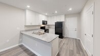 Located at 2715 Statesville Blvd in Salisbury, NC, this well-appointed single-story, three-bedroom, two-bathroom home offers a thoughtfully designed layout with modern finishes throughout. Wood-look plank flooring runs throughout the entire home, providing a cohesive and contemporary aesthetic.

The combined kitchen and living area serves as the heart of the home. The kitchen is equipped with white shaker-style cabinetry, granite countertops, a peninsula with a double stainless steel sink, and black appliances including a refrigerator, range, and microwave. Recessed lighting illuminates the space efficiently. The adjacent living room features neutral warm-toned walls and French doors that open to a private outdoor area, filling the room with natural light.

The spacious primary bedroom includes a large closet with double hanging rods and built-in shelving, along with a window fitted with blinds for light control. The two additional bedrooms are well-sized, each with windows overlooking the surrounding neighborhood. Both bathrooms feature clean white tub-shower combinations with chrome fixtures.

A dedicated in-unit laundry room houses a full-size washer and dryer with an overhead storage shelf. Two additional closets and a hallway connecting all rooms round out this practical and comfortable home.