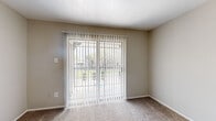 This single-floor, 1-bedroom, 1-bathroom unit offers a thoughtfully arranged layout that maximizes its compact footprint. The living room is a welcoming space finished with neutral-toned carpet and features sliding glass doors dressed with vertical blinds, providing outdoor views and filling the room with natural light. Adjacent to the living area, the galley-style kitchen is equipped with rich dark brown cabinetry, speckled laminate countertops, a double stainless steel sink, and black appliances including a refrigerator and range. Warm hardwood flooring runs throughout the kitchen, adding a touch of character. The bedroom offers a comfortable, carpeted retreat with a ceiling fan and light fixture overhead, a window with outdoor views, and dedicated closet space for storage. Neutral wall tones throughout the unit create a calm, cohesive ambiance. The bathroom is efficiently designed with a dark wood vanity topped with matching speckled countertop, a single sink, a full tub-shower combination with white tile surround, and hardwood flooring that ties back to the kitchen. Clean white trim and subtle, warm neutral walls unify the entire space with a simple, functional aesthetic.
