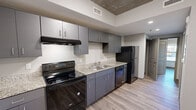 Located at 770 Marshall Acres St in Pigeon Forge, Tennessee, this single-floor unit showcases a contemporary industrial aesthetic throughout. Exposed concrete ceilings and warm wood-look laminate flooring create a striking visual contrast that defines the space's modern character.

The kitchen is well-appointed with slate gray cabinetry, granite-look countertops, and a full suite of black stainless appliances including an electric range, refrigerator, and dishwasher. A double-basin sink and ample upper and lower cabinet storage round out this functional cooking space.

The bedroom features the same wood-look flooring and exposed concrete ceiling, complemented by natural light from a window. Two separate closets provide generous storage options, lending practical versatility to the room.

The bathroom is finished with large-format light tile flooring, a gray vanity with granite-look countertop, and clean white walls that give the space a bright, crisp feel.

Additional areas include a dedicated entryway with durable flooring and a solid panel entry door, as well as a spacious open living area with exposed ductwork accents that reinforce the industrial design theme. The overall layout is efficient and cohesive, offering a well-balanced combination of style and functionality in the heart of Pigeon Forge.