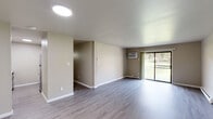 This single-floor unit offers a clean, modern aesthetic with a thoughtfully updated interior. The open living area is finished with light gray luxury vinyl plank flooring and neutral taupe walls, creating a bright and cohesive atmosphere. A wall-mounted air conditioning unit and baseboard heating provide year-round comfort, while a sliding glass door floods the space with natural light and provides direct access to the outdoors, offering views of lush greenery beyond.

The kitchen has been tastefully renovated and features white cabinetry with brushed nickel hardware, granite-look countertops, a classic white subway tile backsplash, a stainless steel sink, and a range hood. The electric range completes a fully functional cooking space.

The unit includes two well-proportioned bedrooms, each with large windows overlooking the surrounding greenery, luxury vinyl plank flooring, and baseboard heating. The rooms offer a calm, neutral palette ideal for a variety of uses.

The bathrooms are finished with white vanities, framed mirrors, and soft neutral wall tones. A dedicated laundry area with a stacked washer and dryer unit is conveniently located within the unit, adding a practical and desirable amenity. Overall, the space presents a fresh, move-in-ready environment with modern updates throughout.