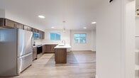 Located at 12531 N Kenosha Ln in Rathdrum, Idaho, this well-appointed one-bedroom, one-bathroom unit offers a thoughtfully designed layout with modern finishes throughout. Light wood-tone flooring flows seamlessly across the entire space, complementing the clean white walls and creating a bright, cohesive aesthetic.

The open-concept kitchen and living area serves as the heart of the unit. The kitchen features rich dark wood cabinetry, a subway tile backsplash, a central island with a built-in sink and pendant lighting above, and a full suite of stainless steel appliances including a refrigerator, range, and microwave. Multiple windows allow natural light to fill the space.

The living area extends naturally from the kitchen and includes access to an exterior door with an adjacent window, bringing in additional natural light and outdoor views.

The bedroom is a comfortable size, offering a closet with a sliding door and a window overlooking the surroundings. A wall-mounted mini-split unit provides efficient climate control.

The bathroom is clean and modern, featuring tile flooring, a walk-in shower, and a dark-wood vanity with light countertops. The dedicated laundry room includes a stacked washer and dryer and an in-unit water heater, adding everyday convenience to this well-equipped residence.