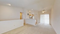 Located at 3025 Fountain Dr. in Beavercreek, Ohio, this single-floor residence offers a well-designed layout with a bright, open-concept living and dining area at its core. The living room is particularly striking, featuring soaring vaulted ceilings adorned with a ceiling fan and light fixture, plush wall-to-wall carpeting, and a sliding glass door with vertical blinds that invites natural light and provides outdoor access.

A white breakfast bar peninsula seamlessly connects the living area to the kitchen, which is outfitted with warm honey-toned cabinetry, white appliances including a range, microwave, and refrigerator, and light tile flooring. Recessed lighting illuminates the kitchen and transition areas throughout.

The bedrooms are carpeted and finished with elegant crown molding, offering a clean, neutral palette. The primary bedroom includes access to a generously sized walk-in closet with wire shelving, providing ample storage. The bathroom features a single-sink vanity with light wood cabinetry, a full tub/shower combo, and tile flooring, maintaining a consistent, clean aesthetic throughout. Additional closet space is available in the hallway. The home's cohesive neutral tones and thoughtful layout make it a comfortable and functional living space.