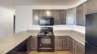 Located at 418 Hein Ave in Sioux Falls, South Dakota, this single-floor unit offers a practical and well-organized layout designed for comfortable everyday living. The open-concept living and kitchen area serves as the heart of the unit, where wood-look luxury vinyl flooring in the kitchen transitions seamlessly into plush carpeting in the living space. The kitchen is outfitted with dark espresso cabinetry, a full suite of black appliances including a refrigerator, electric range, over-the-range microwave, and dishwasher, as well as a sink with ample counter space. A textured ceiling and flush-mount light fixtures provide consistent illumination throughout. The living area is generously proportioned, featuring a ceiling fan with a light kit, a wall-mounted HVAC unit, and a window that allows natural light to brighten the room. A closet with a rod and shelf offers convenient storage just off the main living space. The bathroom is clean and efficiently designed, featuring tile flooring, a dark-toned vanity with a single sink and light countertop, a toilet, and a full tub-shower combination. The neutral white walls and light-toned finishes throughout contribute to a bright, move-in-ready atmosphere that is both functional and easy to personalize.