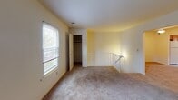 This one-bedroom, one-bathroom residence at Old Forge East in Morris Plains, NJ, offers a practical and comfortable single-floor layout designed to maximize usability. The living area features warm neutral-toned carpeting and a ceiling fan with integrated lighting, creating a relaxed atmosphere. A sliding glass door with vertical blinds connects the living space to the outdoors, allowing natural light to flow in and providing convenient access to the exterior.

The kitchen is well-appointed with warm oak cabinetry offering generous storage, dark speckled countertops, and light tile flooring. White appliances include a refrigerator, electric range, over-the-range microwave, and dishwasher. A window above the sink brings in natural light, making the kitchen a bright and functional workspace.

The bedroom is spacious and carpeted, featuring two windows that overlook outdoor greenery, delivering ample natural light and pleasant views. A closet provides practical storage. Additional carpeted rooms offer flexible space suitable for a home office or den. The bathroom includes a full tub and shower combination with floor-to-ceiling gray tile surround and coordinating tile flooring, providing a clean, modern aesthetic.