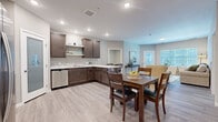 Located at 6620 Chestnut St in Lino Lakes, Minnesota, this well-appointed two-bedroom, two-bathroom residence offers a thoughtfully designed single-level floor plan with modern finishes throughout. The open-concept kitchen and living area serves as the heart of the home, featuring rich dark-toned cabinetry, marble-look countertops, a kitchen island with bar seating, stainless steel appliances, and light wood-look flooring that flows seamlessly throughout the main living spaces. Open shelving adds functional style to the kitchen, while a dedicated dining area accommodates a full-sized table with ease. The living room is bright and welcoming, with large windows that invite natural light and a door providing outdoor access. Both bedrooms offer plush carpeting and windows for natural light, with the primary bedroom providing a comfortable, generously sized retreat. The two bathrooms are finished in a clean, contemporary style with dark wood vanities, white countertops, and light flooring — one featuring a full soaking tub and shower combination, the other equipped with accessibility-friendly grab bars. A dedicated in-unit laundry room with full-sized washer and dryer adds everyday convenience. Three closets provide ample storage throughout the residence.