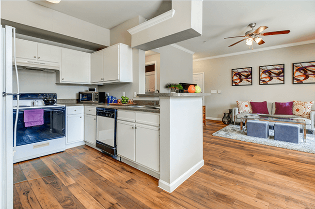 Kitchen with new black and silver Whirlpool appliances, white cabinets with brushed nickel knobs and wood-style floors - Colonnade