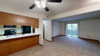 Located at 1000 S Basswood Cir in Bloomington, Indiana, this single-floor, one-bedroom, one-bathroom unit offers a functional and well-organized layout. The open-concept living and dining area is finished with wall-to-wall carpet and features a ceiling fan with light fixture, a textured ceiling, and a sliding glass door that fills the space with natural light and provides access to an outdoor balcony. The kitchen is designed with warm wood cabinetry, a pass-through counter with a double stainless steel sink, white laminate countertops, and black appliances including a range, microwave, and refrigerator. A dedicated dining area sits adjacent to the kitchen, creating a cohesive and efficient living zone. A hallway connects the main living area to the private bedroom, which is comfortably sized with carpeted floors, a window with natural light, a full-wall closet with wood-paneled sliding doors, and direct access to a full bathroom. The bathroom is cleanly finished with tile flooring, a full tub-shower combination, and a vanity with storage. Additional closet space and in-unit laundry provisions further enhance the practicality of this thoughtfully arranged home.