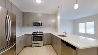 Cedar is a 1-bedroom, 1-bathroom single-floor residence that combines modern design with functional living. The kitchen is a standout feature, showcasing flat-front cabinetry in a warm taupe finish, sleek white quartz countertops, and a subway tile backsplash that adds texture without overwhelming the space. Stainless steel appliances — including a gas range, over-the-range microwave, and dishwasher — provide a professional-quality cooking environment. Pendant lighting above the counter adds a refined touch, while light hardwood flooring runs throughout, contributing to a bright and cohesive aesthetic. The layout is efficiently organized, maximizing the use of available space while maintaining an open and airy feel. Clean lines and neutral tones throughout create a contemporary atmosphere that is both inviting and versatile. The single-floor plan ensures ease of movement and accessibility across all areas of the home. Cedar is well-suited for those seeking a modern, move-in-ready residence with quality finishes and a clean, contemporary design sensibility.