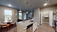 Located at 240 Park Place Blvd in Waxahachie, Texas, this well-designed single-floor residence offers a cohesive blend of modern finishes and functional living spaces. The open-concept layout seamlessly connects the kitchen, dining, and living areas, creating an inviting and spacious atmosphere throughout.

The kitchen serves as a central focal point, featuring a large granite-topped island with an undermount sink, stainless steel appliances including a refrigerator, range, and microwave, and crisp white shaker-style cabinetry. Stylish pendant lights hang above the island, adding warmth and definition to the space. Wood-look flooring runs throughout the common areas, contributing to the home's contemporary aesthetic.

The living area is bright and comfortable, benefiting from multiple windows that allow natural light to fill the room. The dining space sits adjacent, completing the open-concept flow.

The bedroom is a calm retreat, featuring a ceiling fan, natural light from dual windows with views of greenery, and wood-look flooring. A second, more intimate bedroom or guest room is also present, offering a serene atmosphere with neutral tones.

The bathroom is clean and modern, with a full soaking tub and tiled surround. A walk-in closet with built-in shelving provides generous storage and connects directly to the bedroom, enhancing the practical layout of this thoughtfully designed residence.