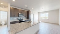 This well-designed two-bedroom, one-bathroom residence in Lakewood, Colorado offers a thoughtfully arranged open-concept floor plan with modern finishes throughout. The kitchen serves as the centerpiece of the living area, anchored by a generous granite-topped island with an undermount sink, dark wood cabinetry extending to the ceiling, a subway tile backsplash, and a full suite of stainless steel appliances including a French door refrigerator, electric range, and built-in microwave. Light wood-look flooring flows seamlessly through the kitchen and main living areas, creating a bright and cohesive aesthetic. Both bedrooms are well-proportioned and feature large windows that invite abundant natural light and offer elevated views of the surrounding Lakewood neighborhood and distant mountains. One bedroom features soft carpeting and a sliding-door closet with built-in shelving, while the other showcases the same light flooring found throughout. The full bathroom is finished with a dark wood double vanity, granite countertops, gold-accented fixtures, and a large mirror, complemented by light flooring and a window for natural ventilation. A dedicated closet provides additional storage. The clean, neutral palette and modern finishes throughout give this residence a fresh, contemporary feel.