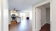 This well-appointed single-floor residence offers a thoughtfully designed open-concept layout that seamlessly connects the kitchen, dining, and living areas. Rich hardwood-style flooring flows consistently throughout the space, lending warmth and continuity to every room.

The kitchen is a functional centerpiece, featuring white cabinetry, gray countertops, a full suite of stainless steel appliances including a gas range, microwave, and refrigerator, and a peninsula that opens toward the main living area. Recessed lighting and a large window flood the kitchen with natural light and provide elevated outdoor views.

The living room is generously proportioned, anchored by a sleek fireplace and a sliding glass door that leads to a private balcony, framing views of palm trees and the surrounding neighborhood. A ceiling fan provides added comfort in this airy, light-filled space.

The bedrooms are calm and neutral, finished in soft gray tones with hardwood-style flooring and windows that invite natural light. One bedroom features a mirrored sliding-door closet, offering practical storage. The bathroom includes a combined tub and shower, a vanity with a speckled countertop, and a large mirror. Clean white walls and neutral finishes throughout create a cohesive, move-in-ready environment.