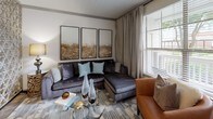 This thoughtfully designed single-floor residence offers a cohesive blend of modern finishes and warm, stylish décor across its key living spaces. The galley-style kitchen is a functional highlight, featuring dark espresso cabinetry, granite countertops, stainless steel appliances including a refrigerator, range, and microwave, pendant lighting, and wood-look flooring that extends into the adjoining areas. The open dining space connects seamlessly to the kitchen and is accented by an ornate floor mirror and decorative room divider, adding a touch of elegance to the layout. The living room is bright and inviting, with large windows that allow generous natural light, complemented by neutral wall tones and ceiling details. Two well-proportioned bedrooms each feature plush carpeting, ceiling fans, large windows with exterior views, and ample room for full bedroom suites. The primary bathroom is equipped with white shaker-style cabinetry, granite countertops, wood-look flooring, and a combination tub and shower with white tile surround. A second bathroom mirrors the same quality finishes and includes a walk-in shower. Throughout the residence, consistent use of granite surfaces, wood-look flooring, and neutral tones creates a unified and polished aesthetic.