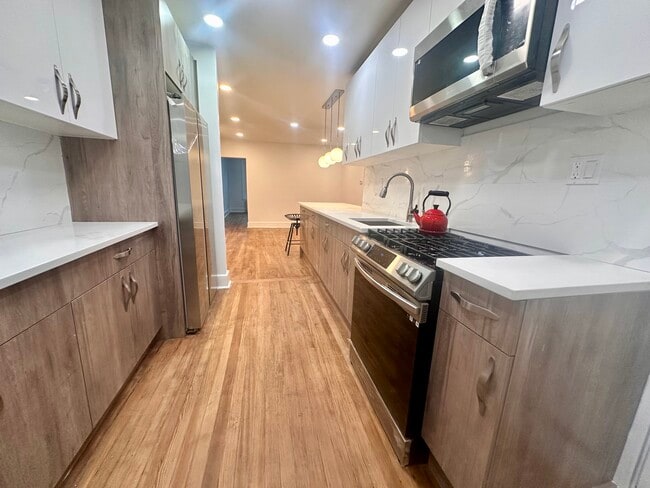 Renovated kitchen with stainless steel appliances, original wood floors, and ample storage. - 328 High St
