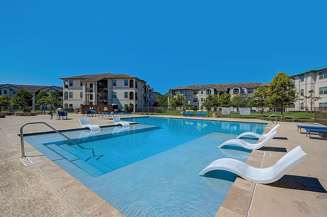 Pool with lounging chairs in water. - Capri Villas at the Lake