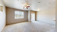 Located at 700 N Haskell St in Central Point, Oregon, this two-story home offers three bedrooms and three bathrooms across two well-proportioned floors. The main level features a bright, open-concept living and kitchen area finished with soft, neutral-toned carpeting and warm beige walls. The living room is equipped with a ceiling fan and receives natural light through a large window and sliding glass doors that open to an outdoor space. The kitchen is outfitted with light maple cabinetry, black appliances including a range, microwave, and refrigerator, and durable tile flooring in a classic pattern. A dedicated laundry area on the main floor accommodates a full-size washer and dryer. The upper floor houses the bedrooms, each carpeted and filled with natural light from windows with horizontal blinds. The generously sized primary bedroom offers comfortable living space. Additional bedrooms are well-sized and share access to the hallway. The home includes a walk-in closet with wire shelving for added storage. Bathrooms feature clean, white tub-shower combinations with chrome fixtures. Vaulted ceilings on the upper level add an airy feel to the home, enhancing its overall sense of space and comfort throughout.