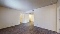 This single-floor residence offers a functional and straightforward layout with consistent wood-style flooring running throughout the living areas, bedrooms, kitchen, and bathrooms. The interior is finished with neutral cream-toned walls and textured ceilings, creating a clean and cohesive aesthetic across the unit.

The galley-style kitchen is equipped with warm wood-toned cabinetry lining both walls, providing ample upper and lower storage. It includes a double-basin sink, electric range with coil burners, a refrigerator, a dishwasher, and a light-colored laminate countertop. A doorway at the end of the kitchen leads to additional interior access.

The bedrooms are generously sized, each featuring the same wood-style flooring and textured ceilings. Windows fitted with vertical blinds allow natural light to filter in, and one room features a large walk-in closet with built-in shelving, offering excellent storage capacity.

The unit includes two bathrooms, each with wood-style flooring, a vanity with wood cabinetry, a mirror with overhead lighting, and a full tub-shower combination. Grab bars are present, adding a practical accessibility feature. HVAC vents are positioned throughout the unit to ensure consistent climate control across all rooms.