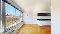 Located at 292 Newark Ave in Jersey City's vibrant Downtown neighborhood, this efficiently designed single-floor unit offers a thoughtful layout across three distinct spaces. The living room is bright and inviting, featuring warm hardwood floors, crisp white walls, and a large picture window that frames neighborhood views and fills the room with abundant natural light. Stylish wall-mounted sconces and a built-in floating shelf add a modern, curated touch to the space. The galley-style kitchen is sleekly outfitted with dark granite countertops, a stainless steel sink, white lower cabinetry, and dark upper cabinets that create a bold two-tone contrast. In-unit washer is also accommodated within the layout, adding everyday convenience. The bathroom maintains the clean, contemporary aesthetic with white shiplap-style tiling, a wall-mounted toilet, a floating sink, and a built-in storage unit. Dark floor tiles ground the space and complement the all-white surfaces. Throughout the unit, consistent hardwood flooring and a neutral white palette create a cohesive, modern feel that maximizes the sense of space. The unit's location on Newark Avenue places it within easy reach of Jersey City's dining, shopping, and transit options.