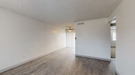 This single-story unit offers a well-organized layout with a variety of updated finishes that give the space a clean, contemporary feel. The entryway greets residents with durable wood-style flooring, neutral gray walls, a textured ceiling, and a front door with glass panel inserts that invite natural light from a large adjacent window fitted with blinds.

The living area continues the wood-style flooring and features a ceiling fan, a ceiling-mounted HVAC vent for climate control, and a vertical blind-covered sliding door that provides access to the exterior. The open, uncluttered layout lends the space a versatile, functional quality.

The kitchen has been notably updated, showcasing gray shaker-style cabinetry, marble-look countertops, a stainless steel sink with a pull-down faucet, a stainless steel dishwasher, and a gas range—providing a practical and attractive workspace.

The bathroom carries the same design sensibility, featuring a white tub-shower combination, a gray vanity with marble-look countertops, a framed mirror, and wood-style tile flooring.

The bedrooms are carpeted for comfort and each includes at least one window with blinds. Notably, one bedroom features an exposed concrete block accent wall, adding a distinct architectural character. A textured ceiling is consistent throughout all rooms.