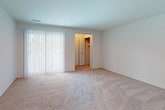 This single-floor unit offers a practical and functional layout with a neutral color palette throughout. The bedrooms are generously proportioned, each featuring plush wall-to-wall carpeting and vertical blind-covered windows that allow natural light to filter in. At least one bedroom includes a walk-in closet with built-in shelving and a hanging rod, providing ample storage. The layout also appears to include an additional carpeted room suitable as a secondary bedroom or flex space, with its own window.

The galley-style kitchen is well-appointed with dark espresso cabinetry, light granite-style countertops, white appliances including a range, refrigerator, and dishwasher, and warm wood-look vinyl flooring. The bathroom areas feature light tile flooring and are finished with matching dark cabinetry and granite-style countertops, maintaining a cohesive design throughout. A secondary bathroom offers a simpler, clean configuration.

A dedicated utility room houses the furnace, water heater, and a full-size washer and dryer, adding significant convenience. The unit's straightforward design emphasizes functionality, with consistent finishes creating a cohesive and move-in-ready environment.