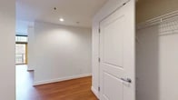 Located in Portland's vibrant Pearl District, this generously sized 5-bedroom, 3-bathroom unit at 900 NW Lovejoy St offers a well-designed, single-floor layout ideal for shared living or larger households. The open kitchen and living area anchors the space, featuring warm honey-toned cabinetry, granite countertops, stainless steel appliances including a refrigerator, range, microwave, and dishwasher, all set atop rich hardwood floors that extend into the living area. Floor-to-ceiling windows and sliding glass doors in the living room flood the space with natural light and open to a private balcony with views of the surrounding neighborhood. The five bedrooms are well-proportioned, with the primary bedroom offering notable space, carpeted floors, and a walk-in closet with wire shelving. Additional bedrooms are bright and carpeted, with some rooms providing city views through large windows. The three bathrooms are clean and functional, each featuring soaking tubs with grab bars for accessibility. A dedicated laundry room with a full-size washer and dryer adds everyday convenience, while two hallways provide smooth connectivity throughout the unit. The overall aesthetic is clean, neutral, and move-in ready.