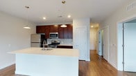 This single-floor residence at 2211 offers a well-designed layout with modern finishes throughout. The open-concept kitchen serves as a central highlight, featuring rich dark-wood cabinetry, stainless steel appliances including a gas range, built-in microwave, and refrigerator, complemented by a light gray tile backsplash. A large white quartz island with an undermount sink anchors the space, providing ample counter space and serving as a natural transition to the adjacent living and dining areas. Pendant lighting above the island adds a contemporary finishing touch.

The living area is bright and open, with warm hardwood flooring extending throughout the main living spaces. Multiple windows invite generous natural light, and a glass-panel door provides access to an exterior entry point. The neutral wall tones create a clean, versatile backdrop throughout.

Bedrooms are carpeted for comfort, with windows that bring in natural light and maintain a calm, understated atmosphere. The bathroom features tile flooring, a dark wood vanity with a granite countertop, a large mirror, and modern light fixtures, reflecting the same cohesive design sensibility found throughout the residence. Overall, the space presents a polished, contemporary aesthetic.